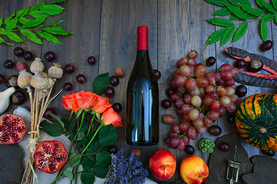 Wine Bottle Beside Grapes Roses And Several Fruits On Brown 1407857